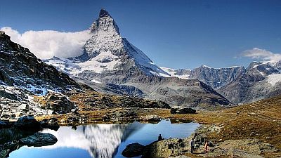 View on the Matterhorn with an Alpine lake and some walkers in the foreground. 