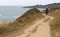 A man walking on a path along the shore