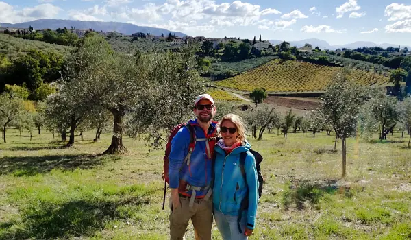 Couple of walkers in an Italian landscape at Montefalco with olive trees and fields.
