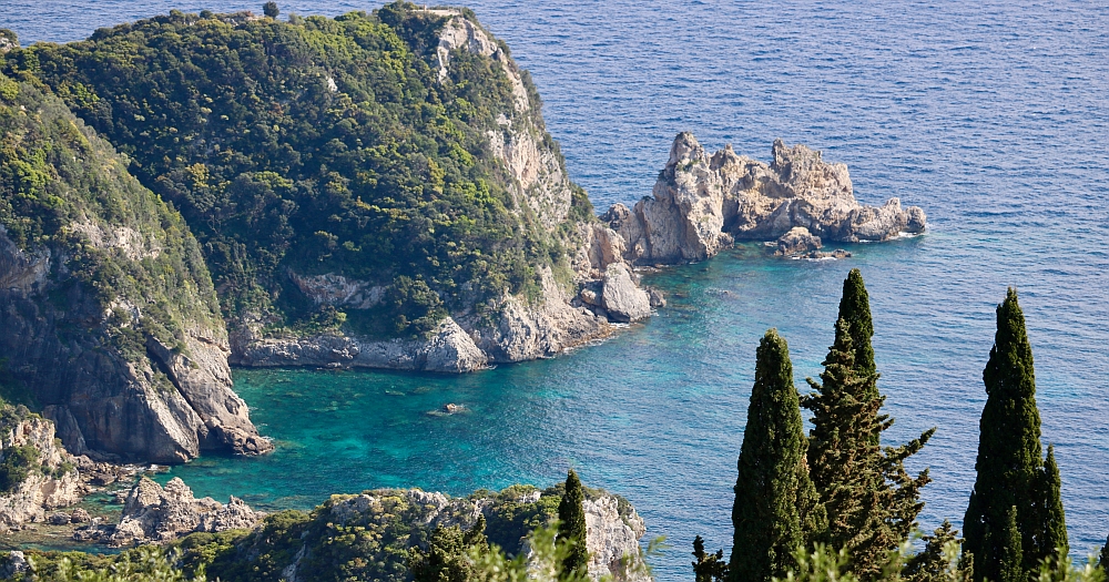 Big rocky hills ending in the sea, green trees as a frame, isle of Corfu, Greece