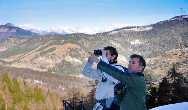 Walking guide pointing out wildlife to a hiker with binoculars