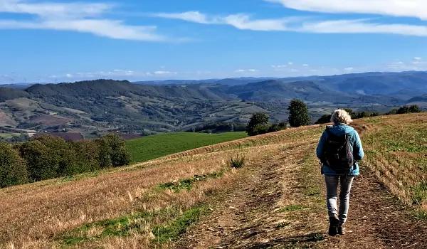Woman with small backpack hiking over a track on the side of a hill over the tarn valley