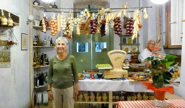 Italian woman proudly standing in her small groceries shop with local produce from Umbria.