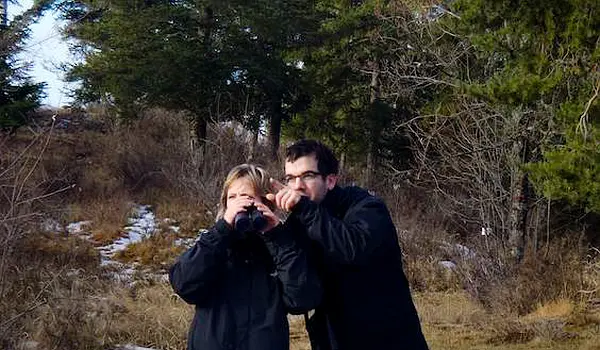 Two people looking through binoculars, excited about spotting wildlife.