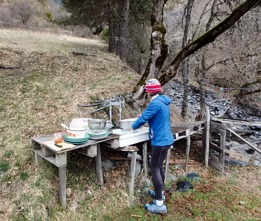 Person washing up outdoors at a basic sink