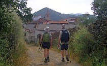 Walkers along a track leading towards a village