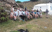 Big group of hikers sitting on a red cliff, posing for a picture