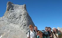 Group of walkers posing for a photo infront of a huge rock