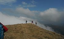 Group of people walking on the endge of a high plain, a low cloud covering the space below
