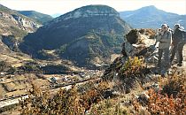 Group of walkers staying on a cliff overlooking a small village in the foot of the mountain infront