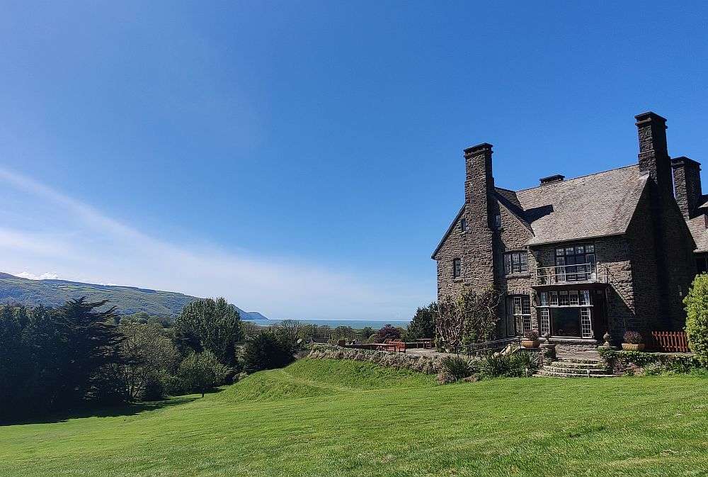 Big house with a big greem meadow infront, a view of the sea in the distance