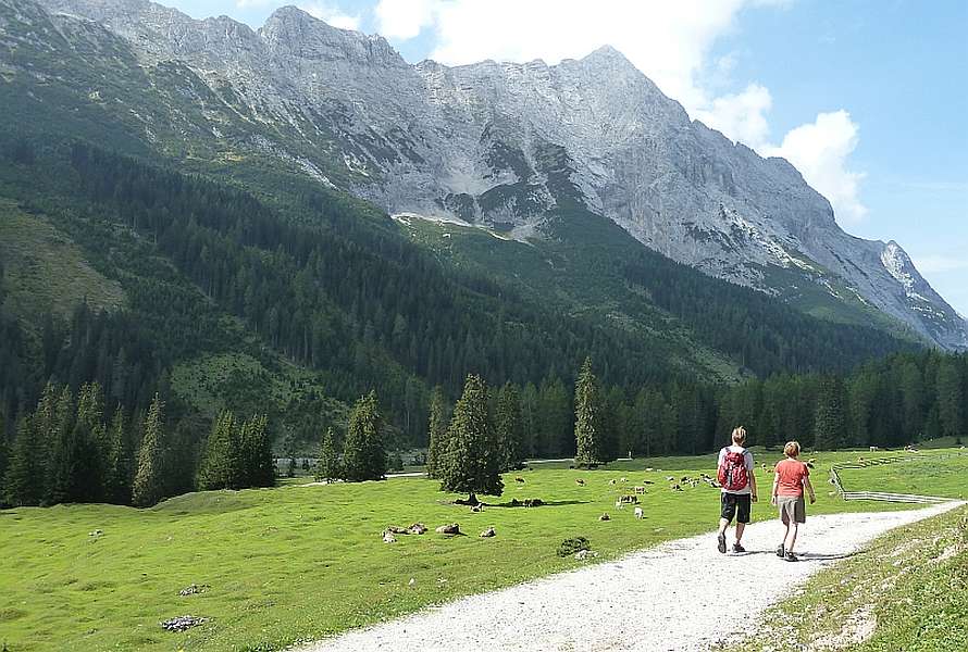 Two hikers walking on a path, snowy mount on the left