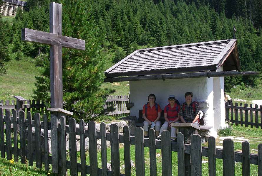 Three hikers sitting for a rest next to a little chapel