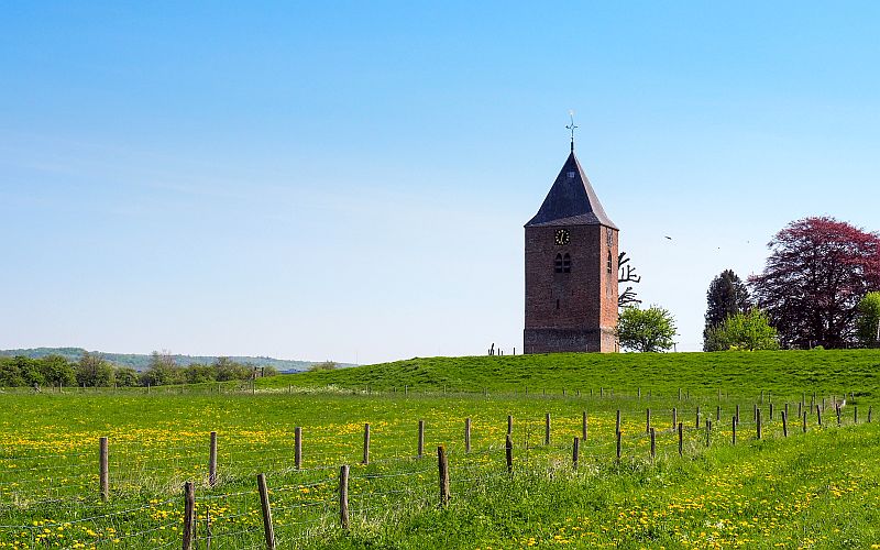 A small church close to the city of Wageningen Church on a small hill in a field of grass and flowers