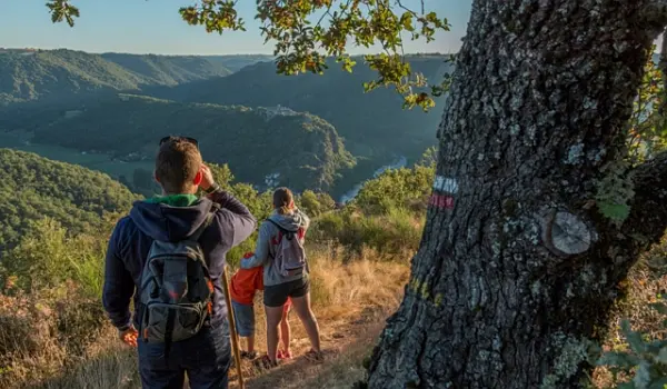 Hikers on a walking path looking towards a valley and mountains in the distance