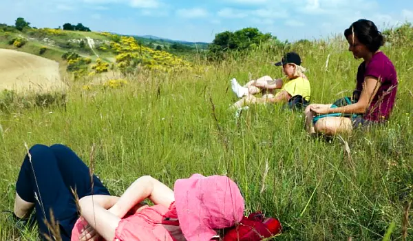 woman-walking-wellbeing-grass-resting Three women resting from walking, sitting in a field overlooking a green landscape