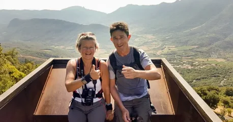 Couple of hikers at a viewpoint overlooking a mountainous valley in France